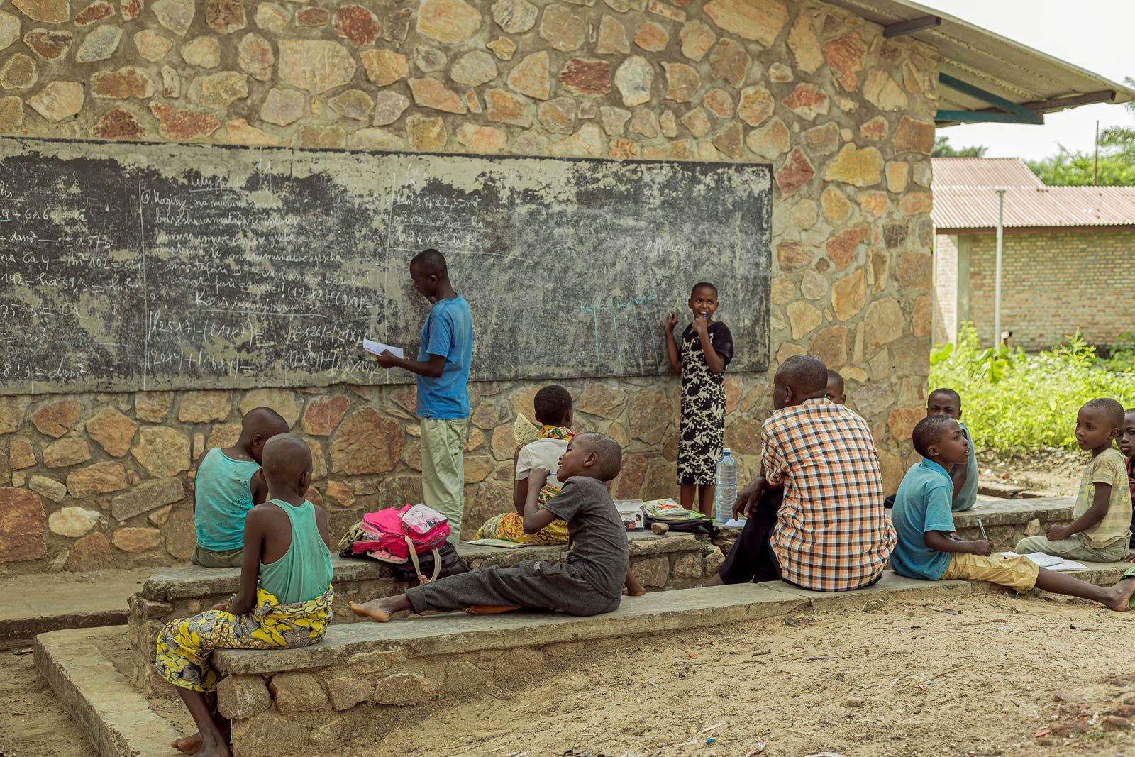 A teacher at a chalkboard in an outdoor classroom